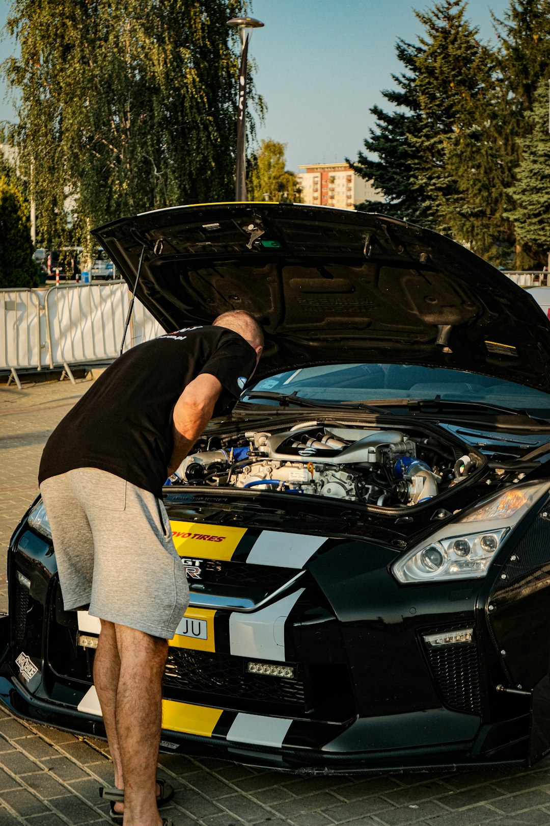 a-man-standing-next-to-a-black-sports-car-akmebzoygie