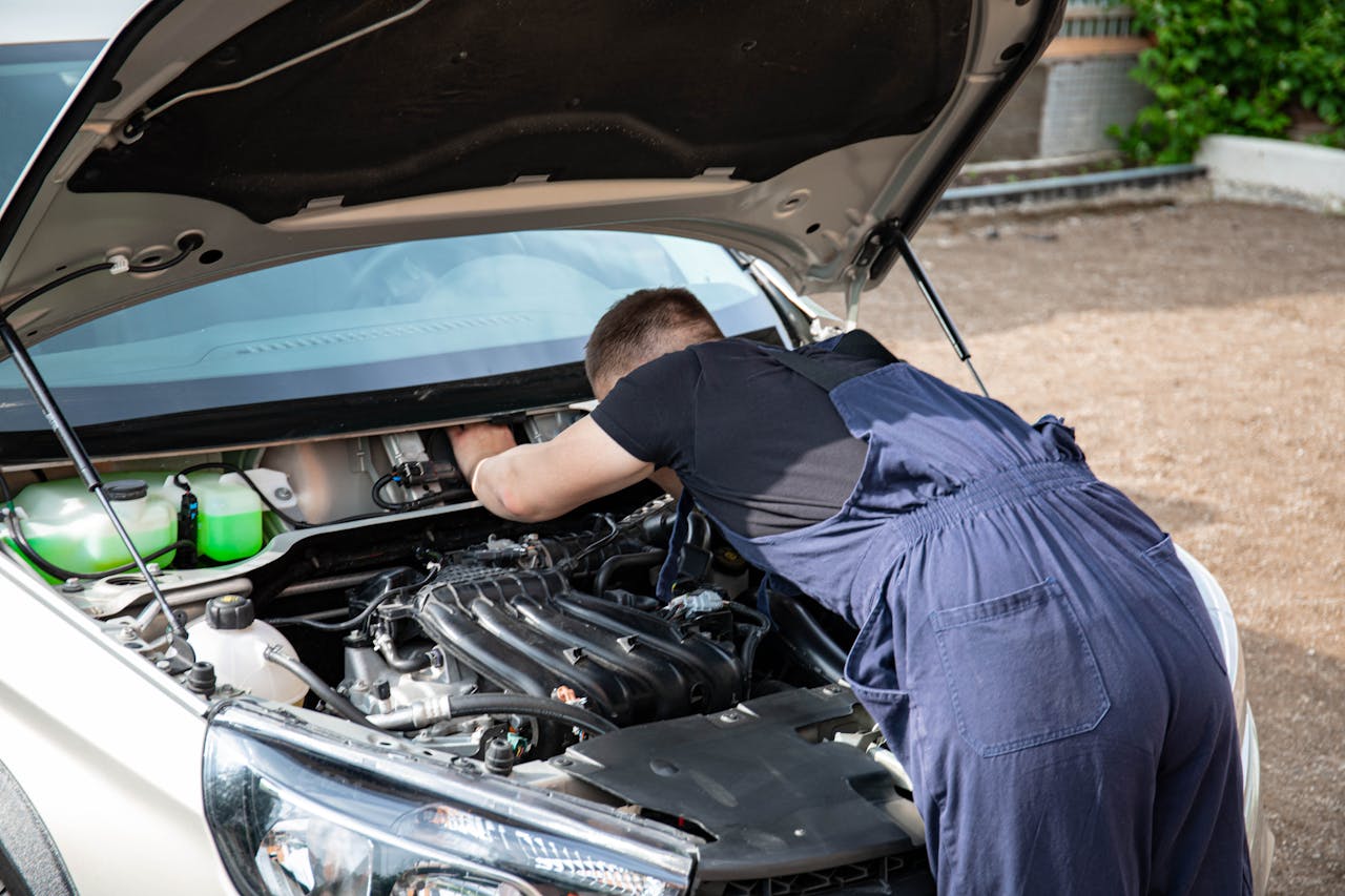 portfolio-06 Mechanic repairing car engine in daylight, showcasing technical skills.